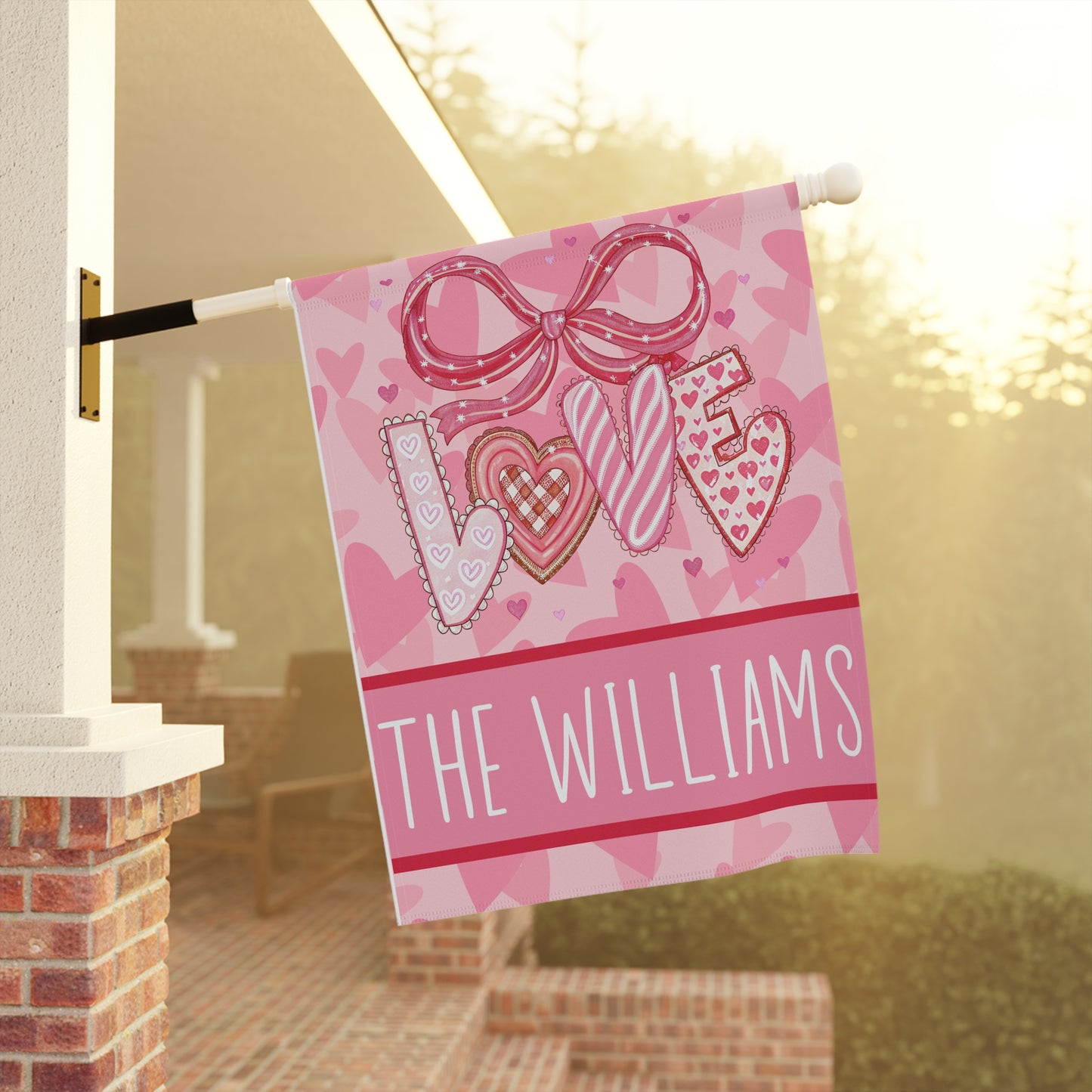 Valentines day garden flag on metal stand in snowy winter garden, pink LOVE design with hearts and personalized family name