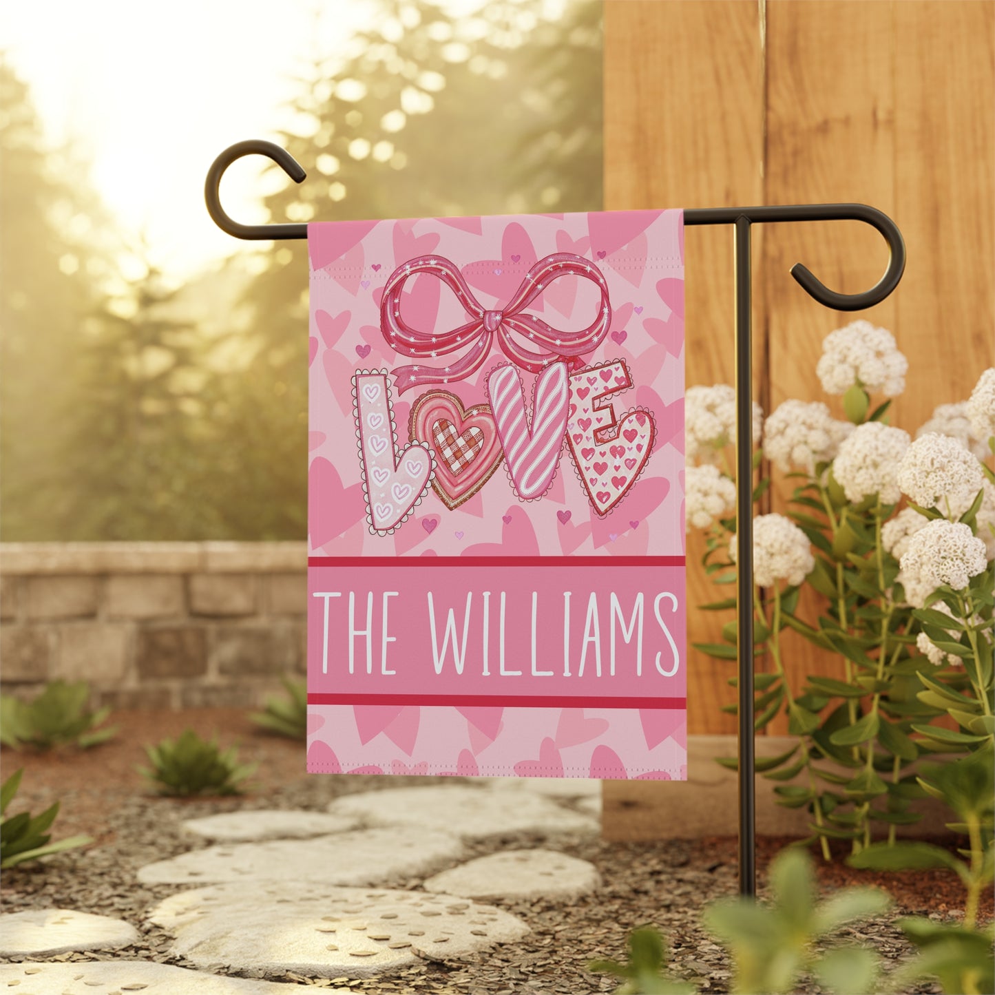 Valentines day garden flag on metal stand in snowy winter garden, pink LOVE design with hearts and personalized family name
