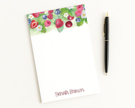 Notepad with fruit design and pen on a white background