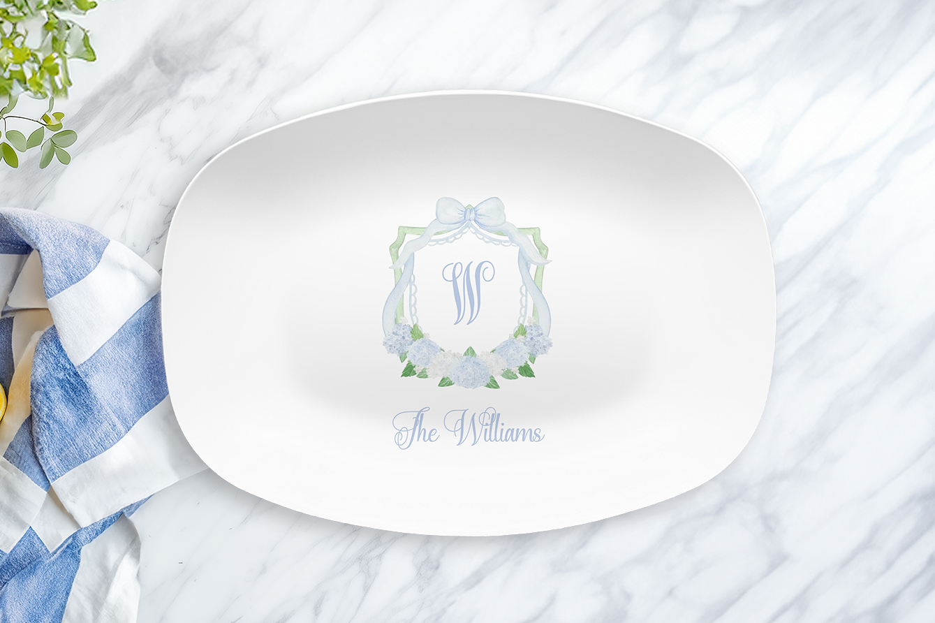 White oval platter with watercolor hydrangea crest and monogram and family name on a marble surface