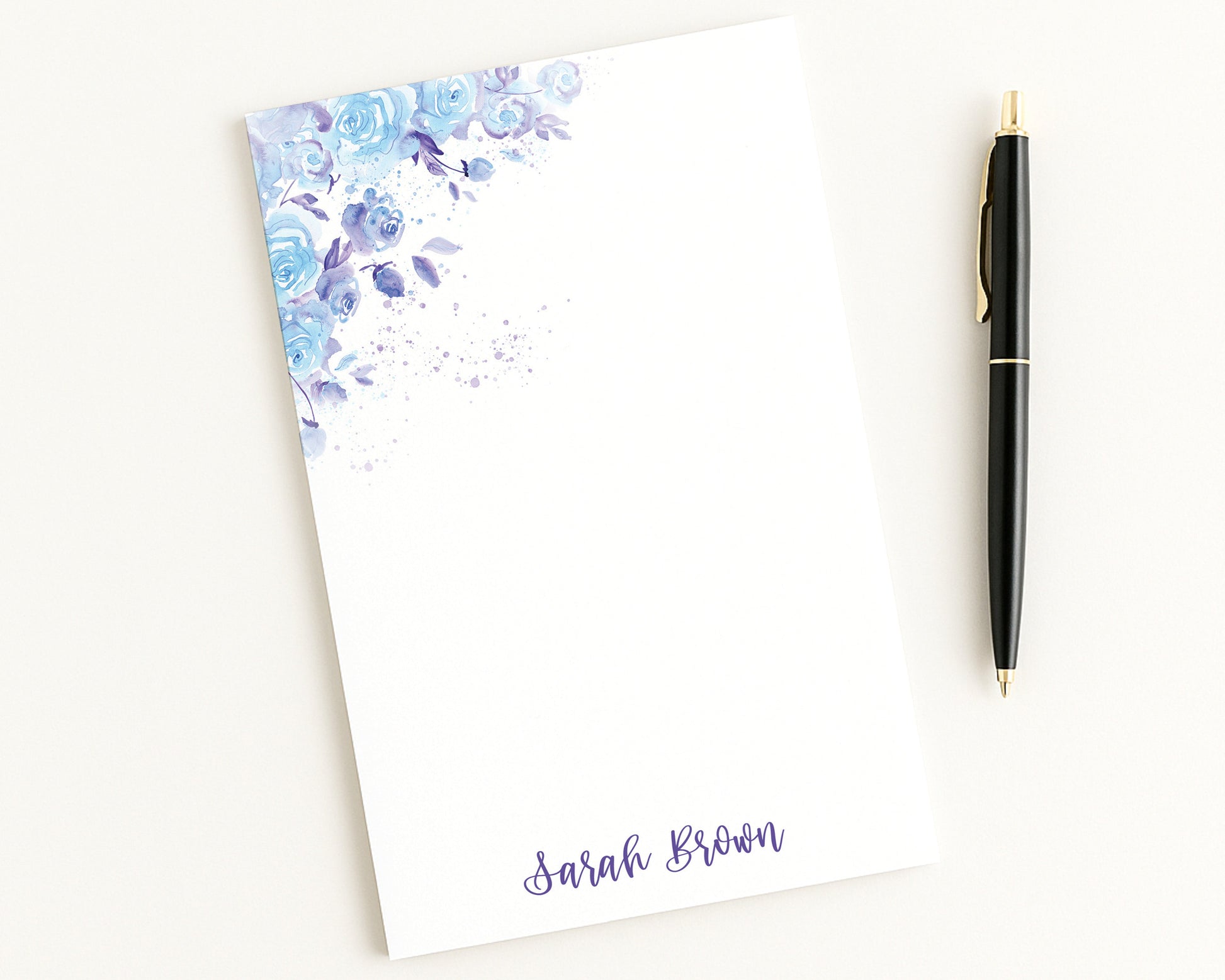 Notepad with floral design and a pen on a white background