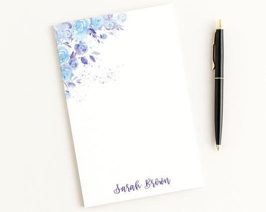 Notepad with floral design and a pen on a white background