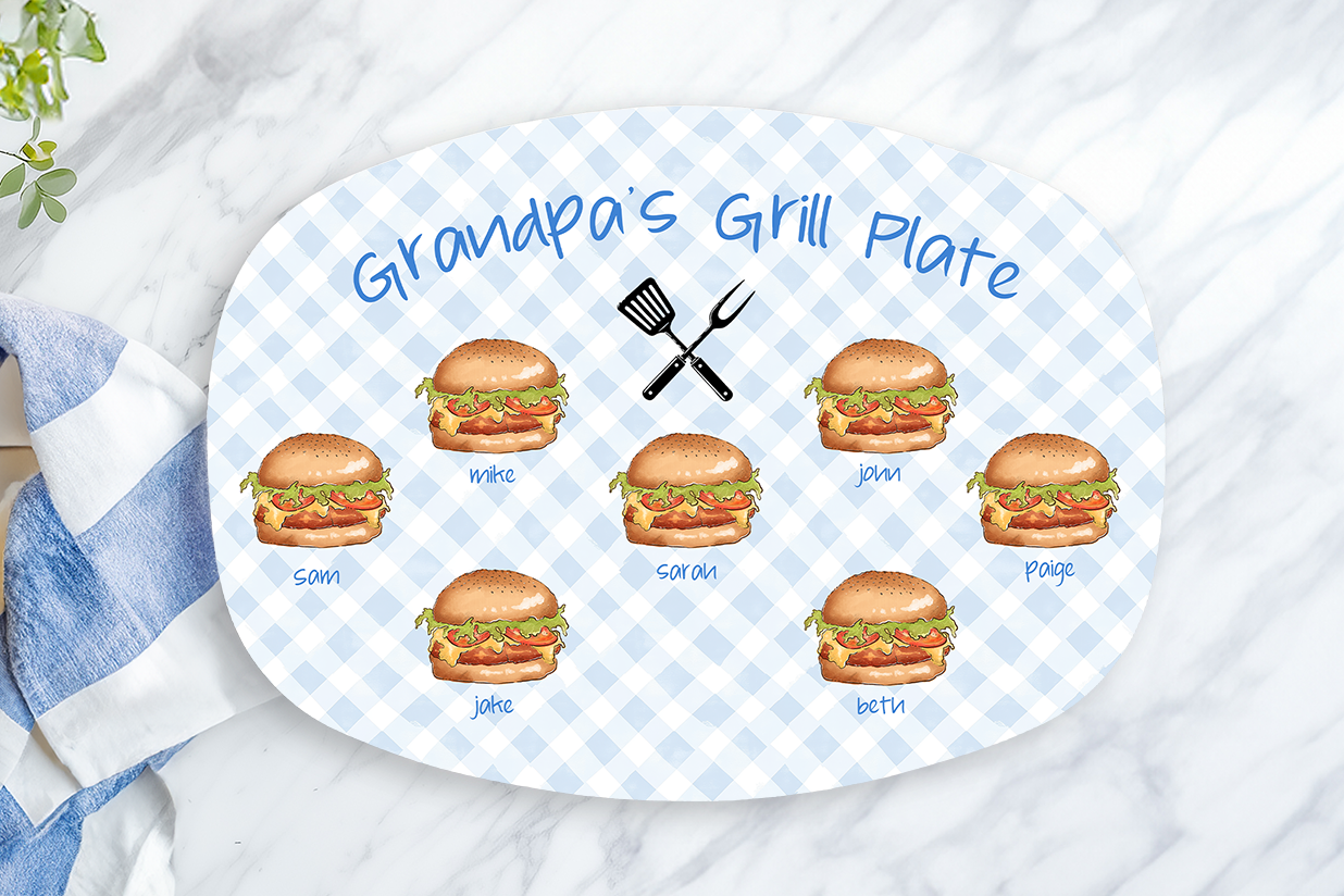 Platter with illustrations of hamburgers and text 'Grandpa's Grill Plate' on a marble surface with a towel and lemon.