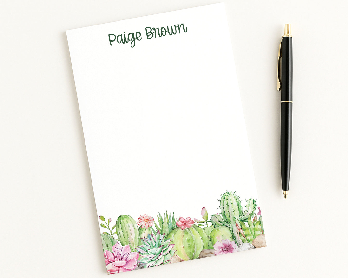 Notepad with cactus design and pen on a white background