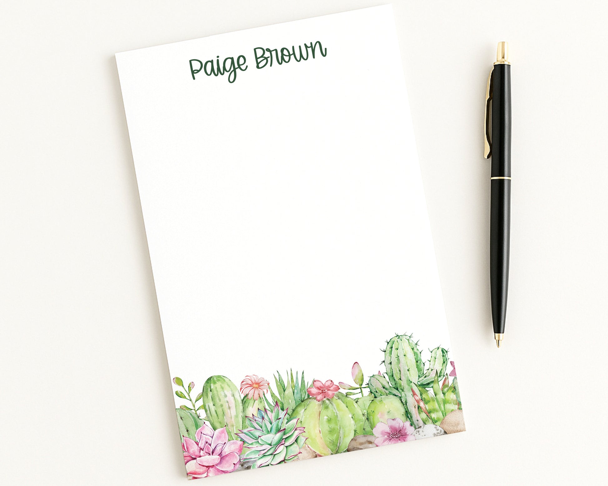 Notepad with cactus design and pen on a white background