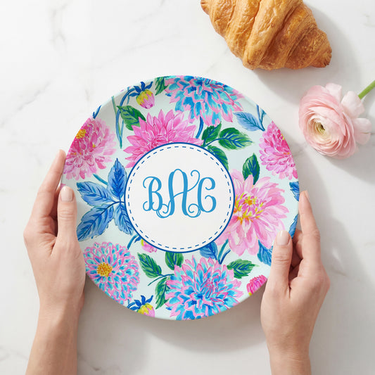 Personalized melamine plate featuring a vibrant pink and blue dahlia floral pattern with a custom three-letter monogram in the center, perfect for personalized table settings and gifts.