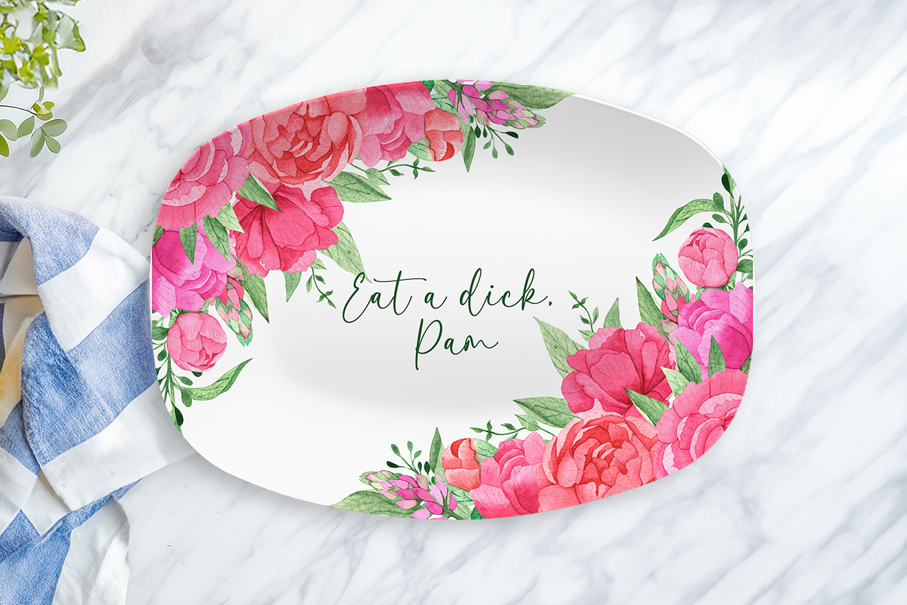 Floral-patterned plate with text on a marble surface with a towel and lemon.