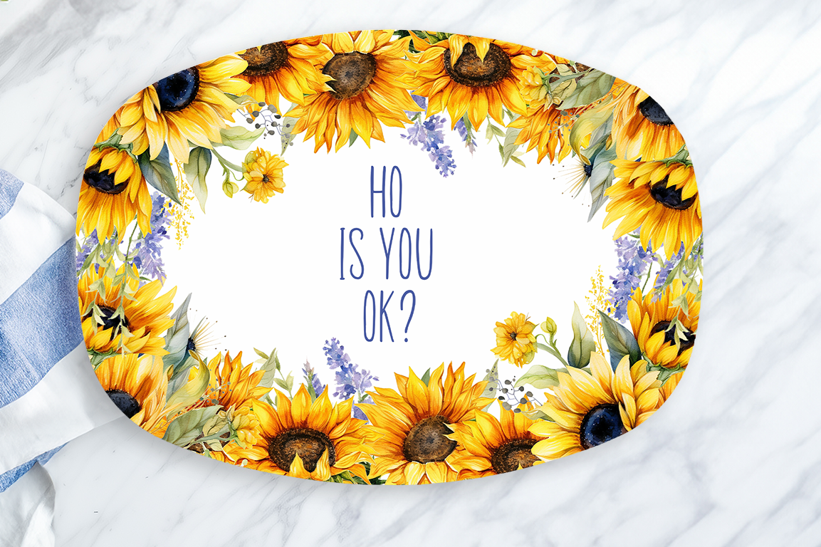 Decorative tray with sunflower design and text on a marble surface with a lemon and towel.