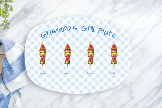 Oval platter with 'Grandpa's Grill Plate' text and grill marks, placed on a marble surface with a towel and lemon.