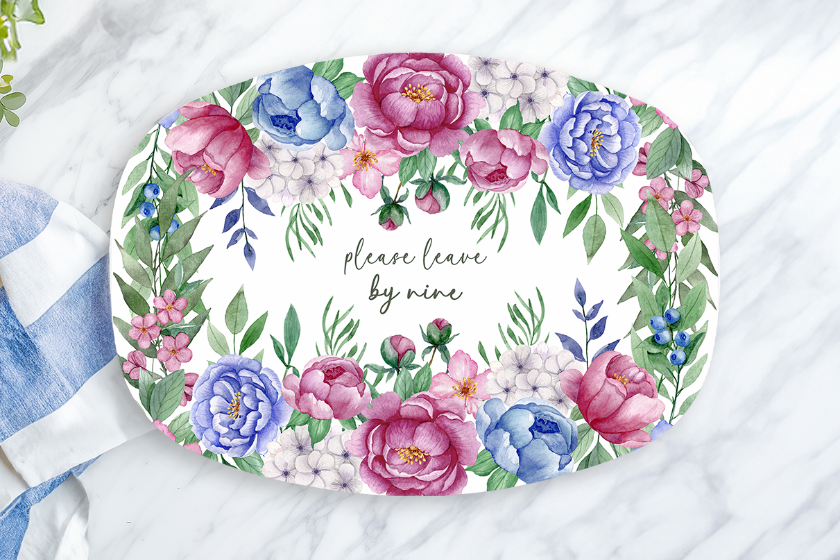 Decorative plate with floral design and text on a marble surface with a towel and lemon.