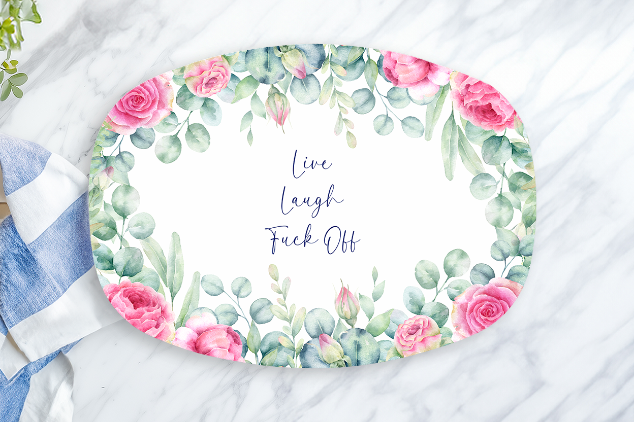 Decorative plate with floral design and text on a marble surface with a towel and lemon.
