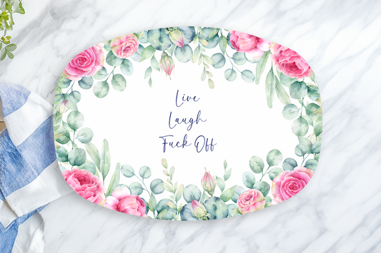 Decorative plate with floral design and text on a marble surface with a towel and lemon.