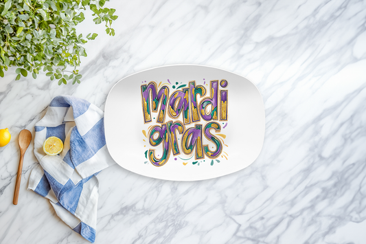 Oval platter with 'Mardi Gras' text on a marble surface with a lemon, napkin, and wooden spoon.