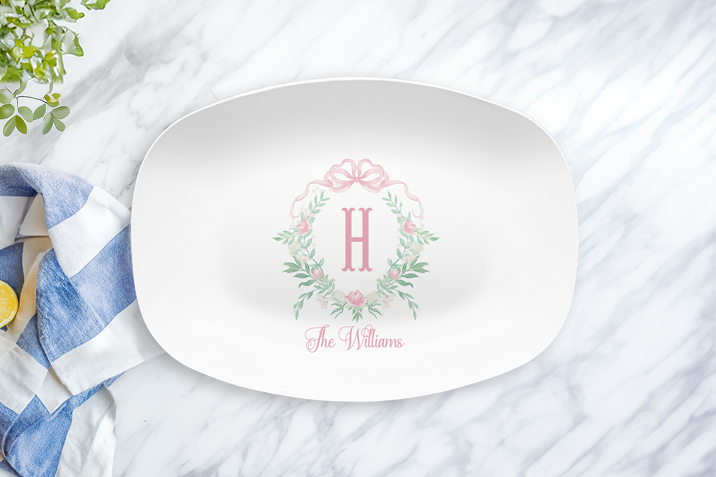 White oval platter with pink peony monogram crest and name on a marble surface