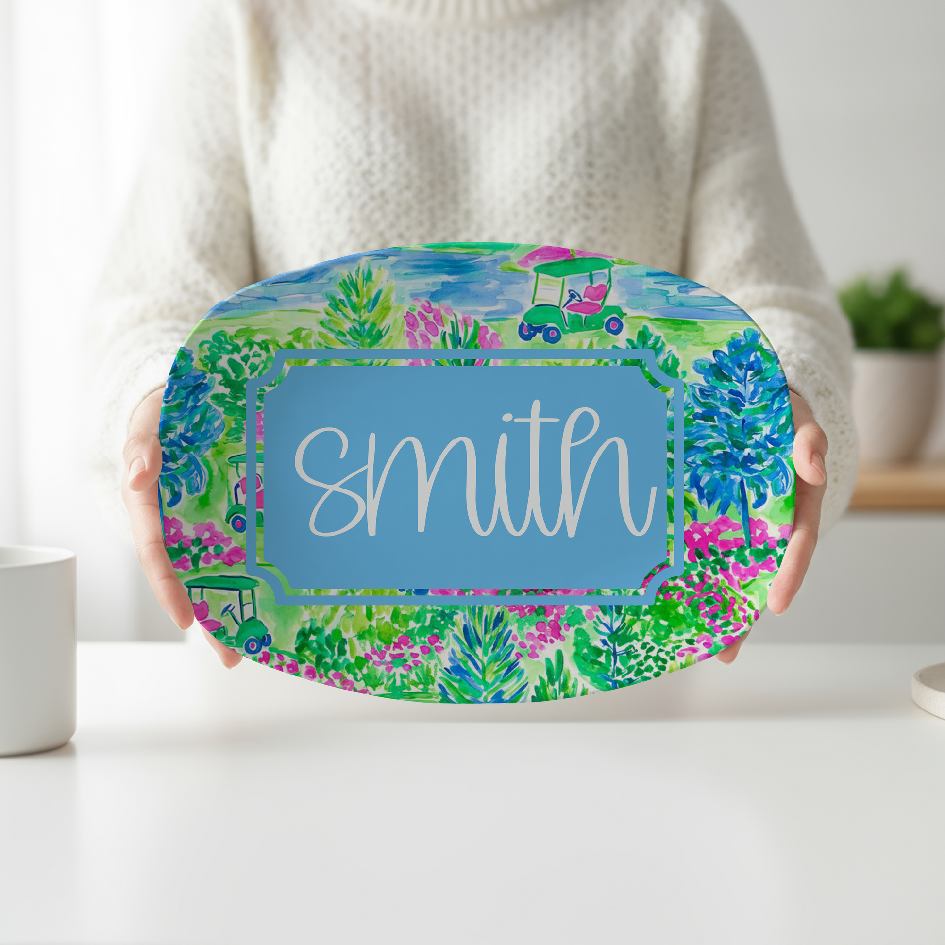 Personalized oval serving platter featuring a colorful watercolor golf course scene with golf carts, lush greenery, and flowers, customized with a family name. Perfect for golfers, country club entertaining, weddings, housewarming gifts, and golf-themed home décor.