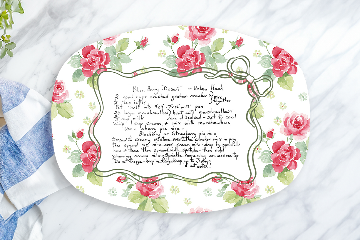Decorative platter with floral design and text on a marble surface with a lemon and towel.