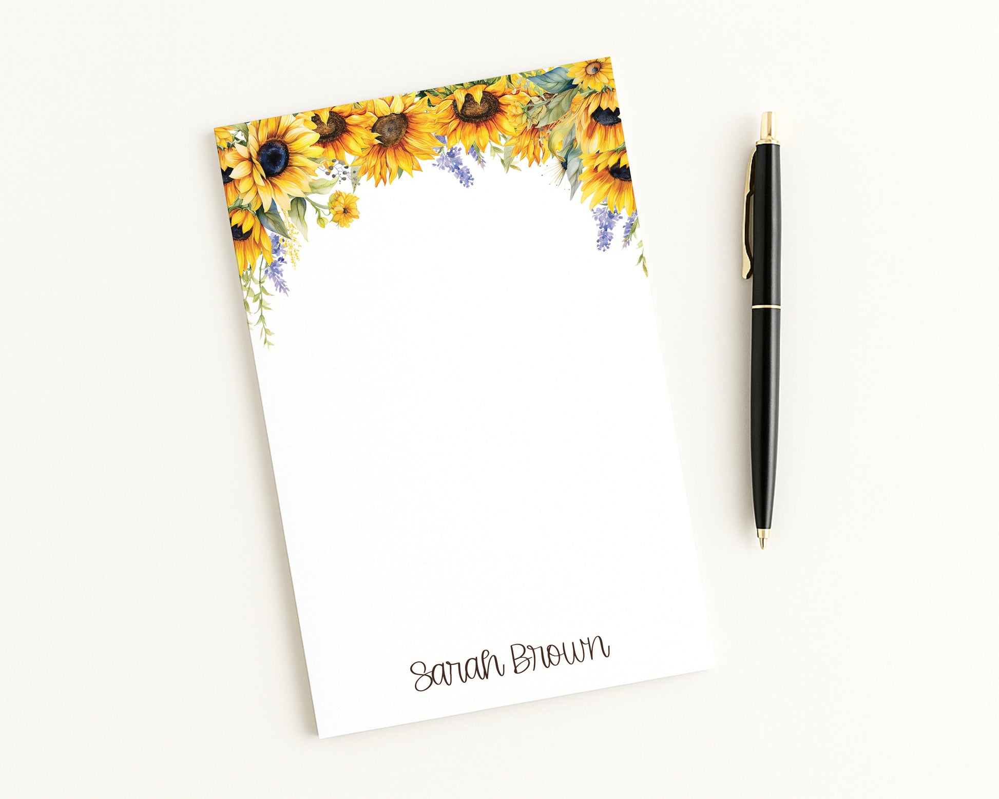 Notepad with sunflower design and a pen on a white background