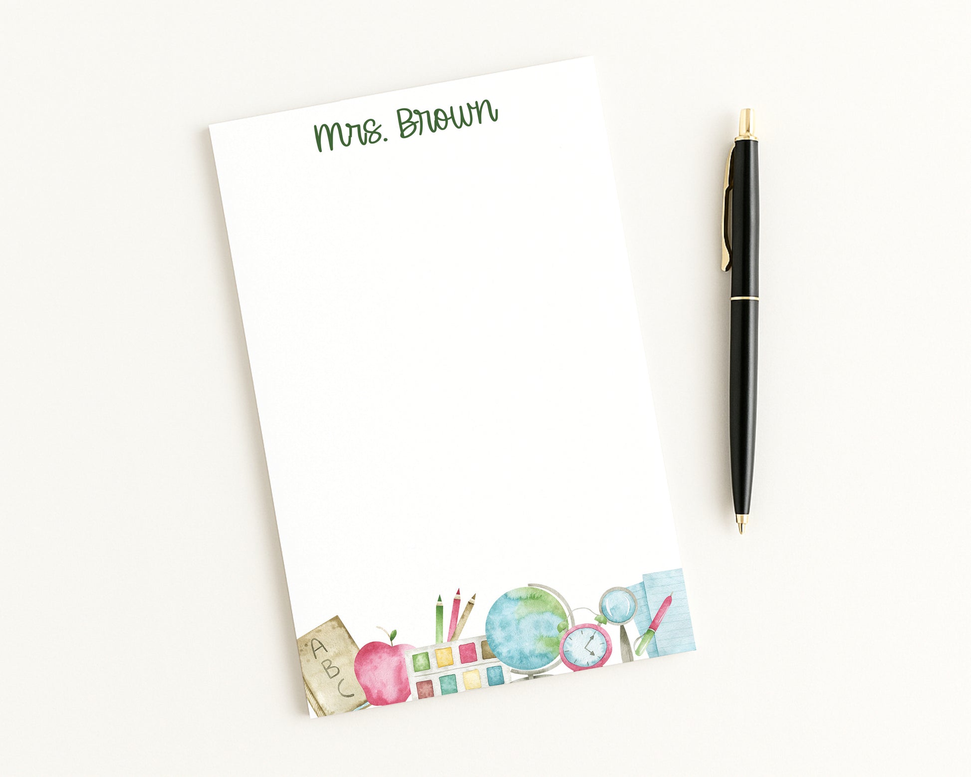 Notepad with teacher-themed design and pen on a white background