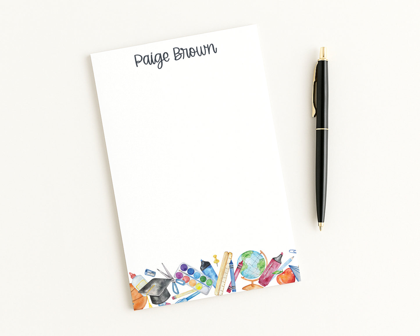 Notepad with colorful stationery illustrations and a pen on a white background
