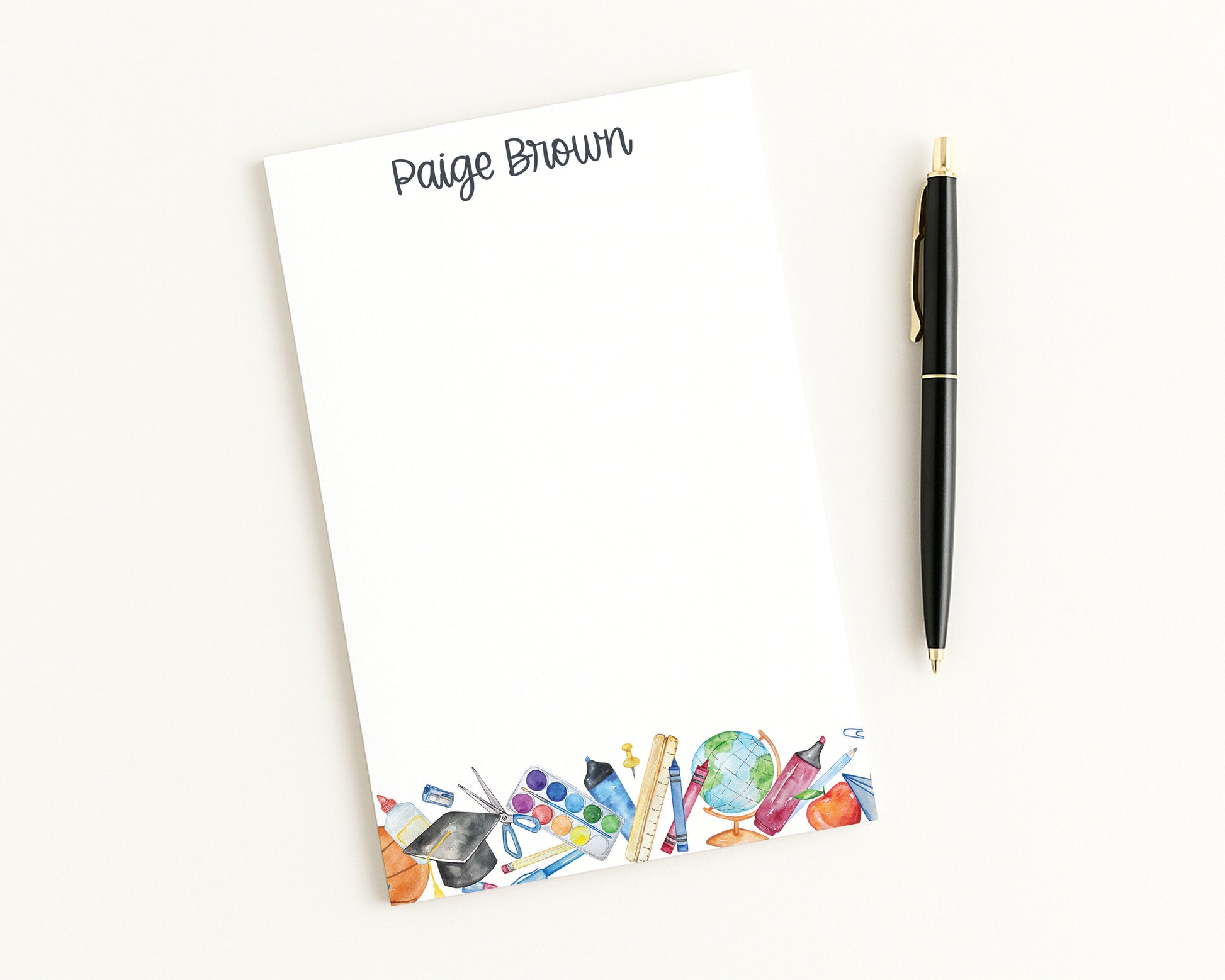 Notepad with colorful stationery illustrations and a pen on a white background
