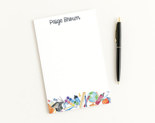 Notepad with colorful stationery illustrations and a pen on a white background