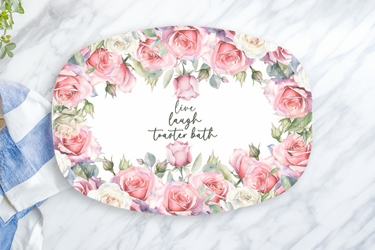 Decorative plate with floral design and text on a marble surface with a lemon and towel.